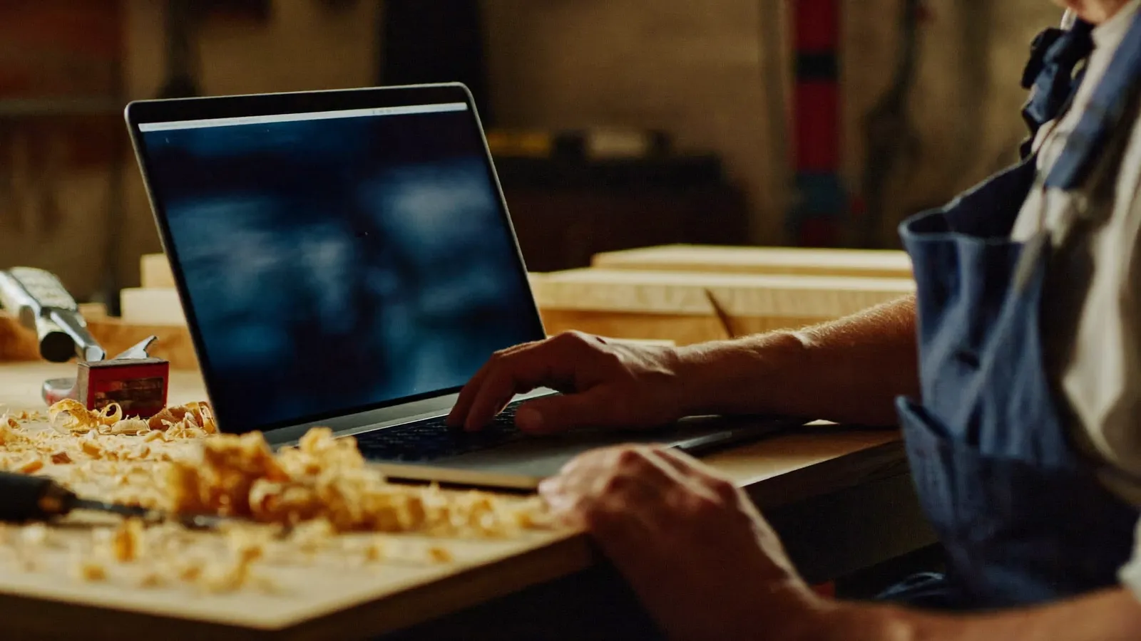 Artisan menuisier consultant son site web sur un ordinateur portable dans son atelier